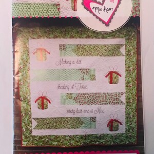 May include: A green and white quilt with a Christmas theme. The quilt features a white background with green and red patterned fabric strips. The quilt is decorated with small red and white gift boxes and the text "Making a list, checking it twice, every last one is nice." The quilt is labeled "Washi Tape #2343".