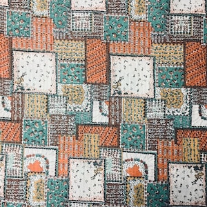 May include: A fabric with a patchwork design featuring squares in various colors. The squares include white, orange, teal, brown, and yellow. Some squares have floral patterns, while others have striped or dotted designs.