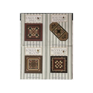 May include: Four quilt patterns from Lodge & Lakeside's Thimbleberries collection. The patterns are "Lakeland Pines", "Bear Paw Runner", "Forest Bloom", and "Woodland Stars". Each pattern features a different design with a rustic, woodland theme.