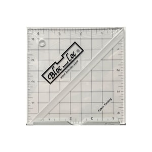 May include: A clear, square quilting ruler with black grid lines and measurements in inches. The ruler has a diagonal edge and a black logo that reads "Bloc Loc" with the website address. The text "Patent Pending" is also visible.