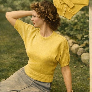 May include: A woman wearing a yellow short-sleeved sweater and a gray skirt sits on the grass. A matching yellow cardigan is displayed above. The sweater and cardigan have a ribbed hem and cuffs. The woman is wearing a gold watch.