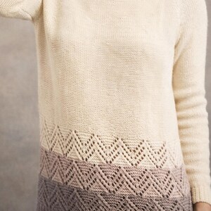 May include: Cream-colored turtleneck sweater with a decorative openwork pattern in shades of beige and mauve. The sweater has long sleeves and a ribbed hem. A cozy and stylish knitwear piece.