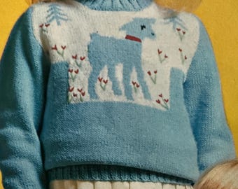May include: A light blue knitted sweater with a high collar. The sweater features a white panel with a light blue lamb design, red collar, and red flower accents. The sweater is part of a children's clothing collection.