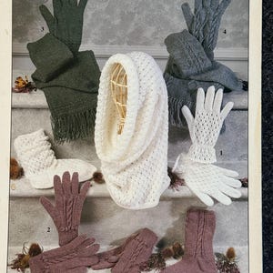 May include: A knitting pattern booklet featuring a variety of knitted items, including a white cowl, a pair of white gloves, a pair of purple gloves, a pair of purple socks, a pair of gray gloves, and a green scarf. The pattern is for 4 ply yarn and is from the brand Sirdar.
