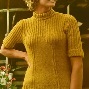 May include: Mustard yellow ribbed knit sweater with a high neck and short sleeves. The sweater has vertical ribbing and a fitted silhouette. The model is wearing a cream-colored skirt. The image has a vintage aesthetic.
