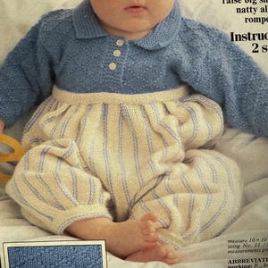 Op de afbeelding: Een baby in een gebreide romper in blauw en crème. De bovenkant is blauw met een kraag en knopen, de onderkant is crème met blauwe strepen. De afbeelding komt uit een breipatroon.