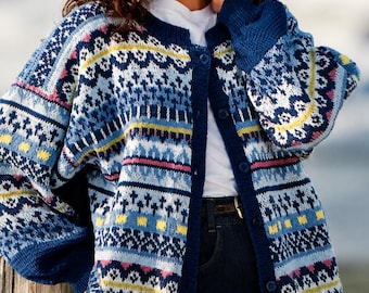 May include: A long-sleeve button-down cardigan featuring a complex knit pattern in shades of navy blue, light blue, white, yellow, and pink. The garment has a solid navy blue ribbed trim along the neckline, cuffs, and front button placket.