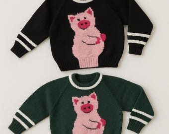 May include: Two knitted jumpers, one black and one dark green, each with a pink pig design on the front. Both jumpers have white stripes on the sleeves and a white trim around the neckline.