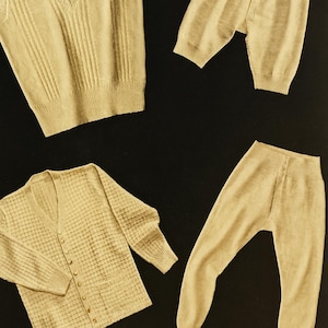 Könnte beinhalten: Eine Kollektion beigefarbener Strickwaren, darunter eine V-Ausschnitt-Weste, eine Strickjacke mit Knöpfen und zwei Hosen. Die Strickwaren haben ein geripptes und strukturiertes Design. Die Artikel sind auf schwarzem Hintergrund angeordnet.
