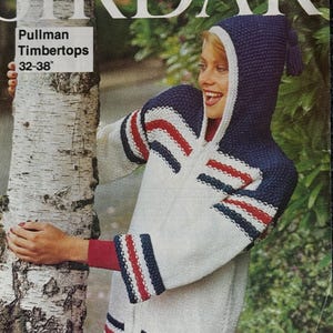 May include: A vintage Sirdar knitting pattern cover featuring a white, navy, and red hooded zip-up sweater. The sweater has striped accents on the sleeves and hem. The text "Pullman Timbertops 32-38" is visible.