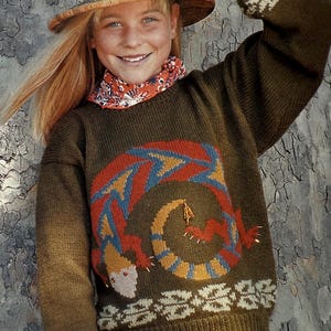 Könnte beinhalten: Olivgrüner Pullover mit farbenfrohem Echsenmuster. Der Pullover hat einen Rundhalsausschnitt und lange Ärmel mit gemusterten Bündchen. Das Echsenmuster enthält rote, blaue und gelbe Details. Ein Strohhut und ein gemusterter Schal ergänzen den Look.