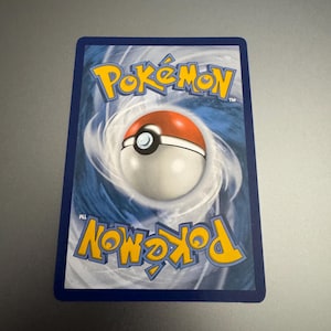 May include: The back of a Pok&eacute;mon trading card. The card features a blue background with a swirling pattern. The Pok&eacute;mon logo is in yellow at the top and bottom, with a red and white Pok&eacute; Ball in the center.
