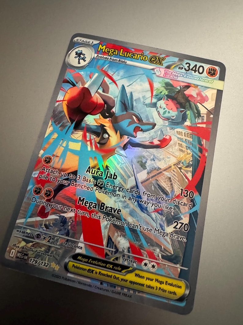Puede incluir: Una tarjeta coleccionable Pok&eacute;mon Mega Lucario EX hologr&aacute;fica. La tarjeta presenta un personaje Lucario azul y rojo con el texto "Mega Lucario EX", "Aura Jab" y "Mega Brave". La tarjeta tiene 340 HP.
