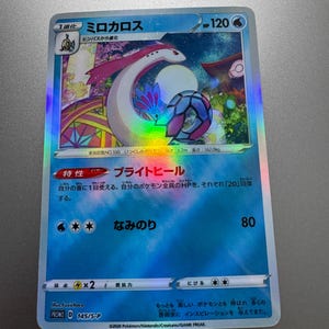 May include: A holographic Pokémon trading card featuring Milotic. The card has Japanese text and a colorful illustration of a serpentine creature. The card's HP is 120, and it has a blue and white background.