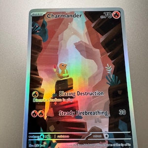 May include: A holographic Charmander Pokémon trading card. The card features a colorful illustration of Charmander in a canyon setting. Text includes "Charmander", "Blazing Destruction", and "Steady Firebreathing". The card is numbered 168/165.