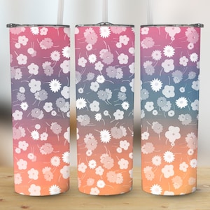 May include: Three stainless steel tumblers with a floral design. The tumblers feature a gradient background of orange, purple, and blue. White flowers are scattered across the surface. Each tumbler has a black lid and a straw.