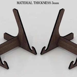 May include: Two wooden display stands with a dark brown finish. Each stand has a curved back and a horizontal base with a slot. The text "MATERIAL THICKNESS 3mm" is at the top.