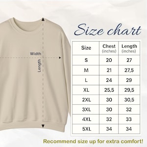 Op de afbeelding: Een beige sweatshirt met een maattabel. De tabel toont borst- en lengtematen in inches voor maten S tot 5XL. De tekst "Beveel een maat groter aan voor extra comfort!" staat onderaan.