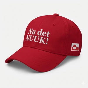 May include: A red baseball cap with white embroidered text that reads "Nu det NUUK!" on the front. The cap features a curved brim and a small Greenlandic flag patch on the side. The hat is a classic, casual accessory.