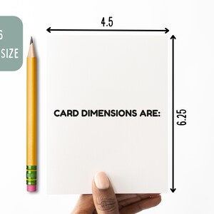 May include: A white A6 greeting card with the text CARD DIMENSIONS ARE: printed in black. The card measures 4.5 inches in width and 6.25 inches in height, as indicated by black arrows and a yellow pencil placed vertically beside it.