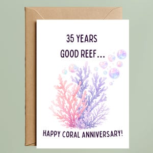 May include: A white greeting card with a brown envelope featuring a watercolor illustration of pink and purple coral reefs and floating bubbles. The text reads 35 YEARS GOOD REEF... HAPPY CORAL ANNIVERSARY! in a dark sans-serif font.
