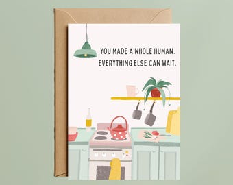May include: Greeting card with a kitchen scene illustration. The card features a red and white polka dot teapot on a stove, a hanging green lamp, and the text: "YOU MADE A WHOLE HUMAN. EVERYTHING ELSE CAN WAIT."