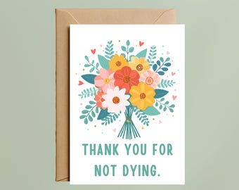 Puede incluir: Una tarjeta de felicitación blanca con una colorida ilustración de un ramo de flores con pétalos rojos, amarillos y rosas, hojas verdes y pequeños corazones rojos. El texto "THANK YOU FOR NOT DYING." aparece en letras mayúsculas de color verde azulado.