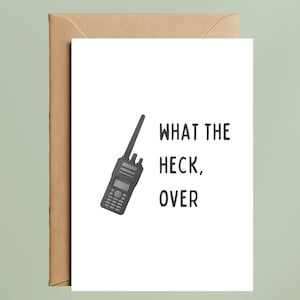 May include: A white greeting card with the text "WHAT THE HECK, OVER" and a black and gray walkie-talkie illustration. The card is inside a brown envelope, set against a light green background.