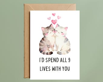 May include: A greetings card with a watercolour illustration of two cats, a grey tabby and a white cat with grey patches, touching noses. Pink hearts float above. The text reads, "I'D SPEND ALL 9 LIVES WITH YOU."
