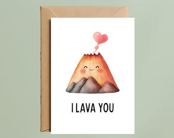 May include: A greeting card featuring a watercolor illustration of a smiling volcano with a heart-shaped plume. The text "I LAVA YOU" is written in black below the volcano. The card is inside a brown envelope.