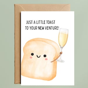 May include: Greeting card with a cartoon illustration of a slice of bread holding a champagne glass. The card reads "JUST A LITTLE TOAST TO YOUR NEW VENTURE!" The card is inside a brown envelope.