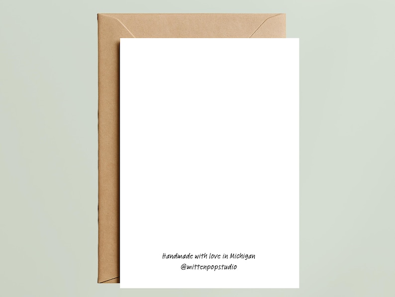 May include: A white rectangular greeting card with a brown kraft paper envelope. The bottom center of the card features black text that reads: Handmade with love in Michigan @mittenpopstudio. The card is blank and oriented vertically.