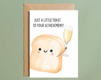 May include: A white greeting card featuring a cartoon slice of bread with a smiling face and pink cheeks, holding a glass of champagne. The text above the bread reads, JUST A LITTLE TOAST TO YOUR ACHIEVEMENT! The card is paired with a brown envelope.