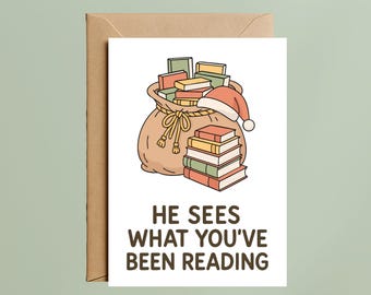May include: Greeting card with a brown envelope. The card features a cartoon illustration of a sack overflowing with books and a Santa hat. The text on the card reads: "HE SEES WHAT YOU'VE BEEN READING."