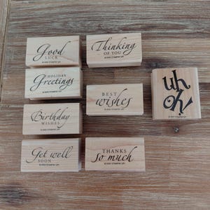 May include: A collection of eight rectangular wooden rubber stamps featuring various phrases including Good Luck, Thinking of You, Holiday Greetings, Best Wishes, uh oh, Birthday Wishes, Get well SOON, and THANKS So much, all marked 2005 Stampin Up.