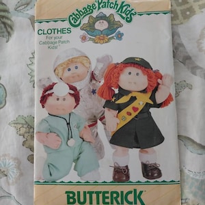 May include: A vintage Butterick sewing pattern for Cabbage Patch Kids clothes. The cover features illustrations of Cabbage Patch Kids dolls dressed as a doctor, astronaut, and scout. The pattern number is 3728.