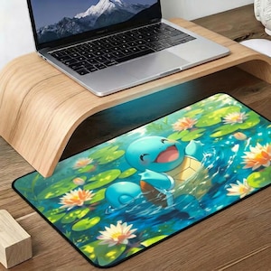 May include: A rectangular desk mat featuring a colorful illustration of a light blue turtle-like creature swimming in a pond filled with green lily pads and white and orange water lilies. The mat has a black border and a smooth surface finish.