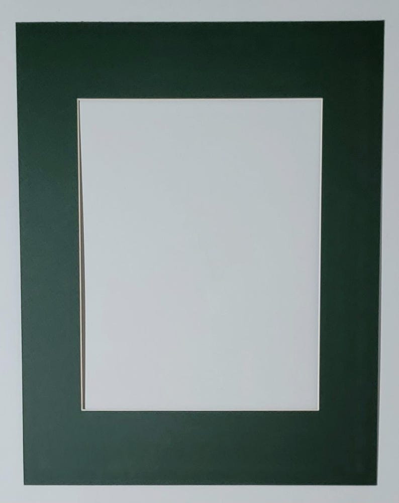 May include: A white picture frame mat with a dark green border and a rectangular opening. The mat is set against a white background, creating a clean and simple aesthetic. Ideal for showcasing photographs or artwork.