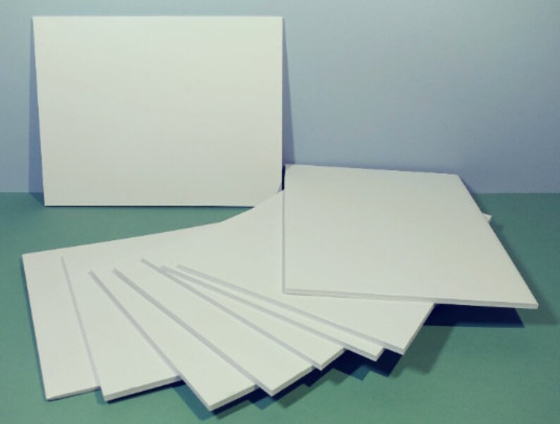 May include: A collection of white foam boards of varying sizes, arranged on a teal surface against a light blue backdrop. The boards are rectangular and appear to be unused, with clean, smooth surfaces. The arrangement suggests a crafting or art supply theme.
