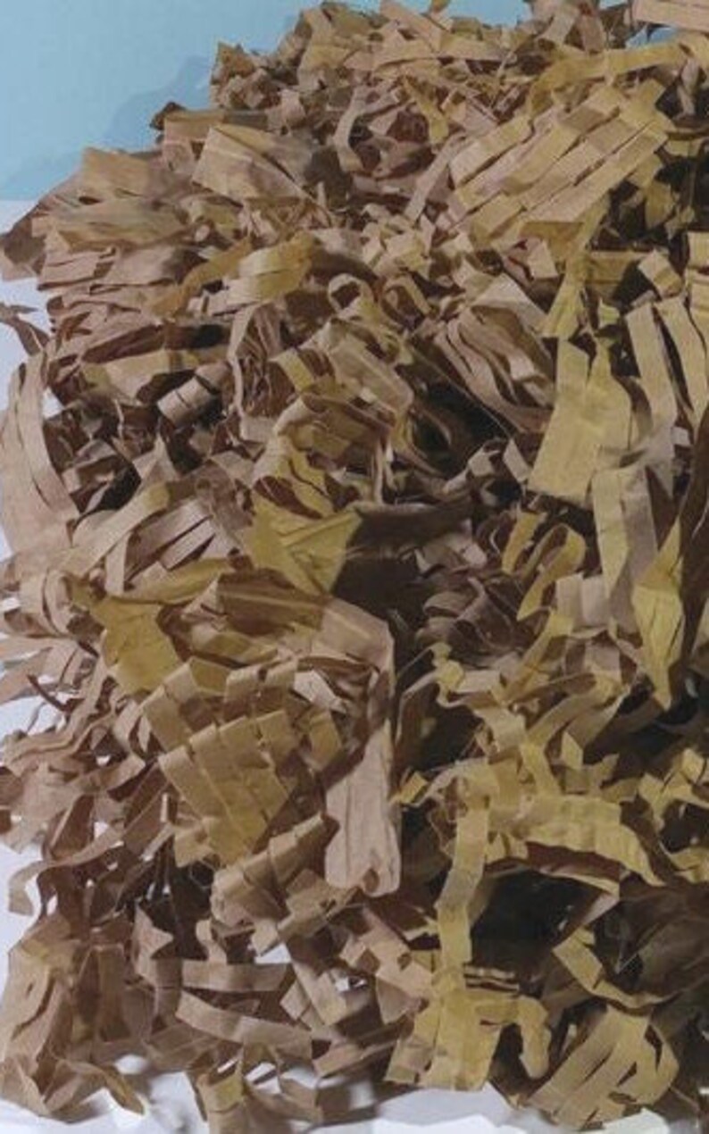 May include: A close-up of brown and tan shredded paper, commonly used as packing material for shipping fragile items.