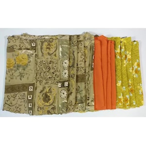 May include: A collection of fabric scraps in various patterns and colors, including brown, yellow, orange, and white. The fabrics feature floral, geometric, and abstract designs.