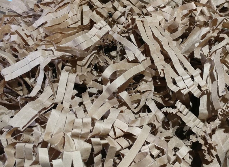 May include: A close-up of brown shredded paper, commonly used as packing material for shipping fragile items.