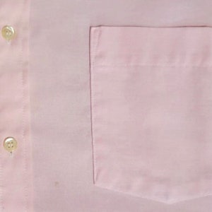 K&ouml;nnte beinhalten: Ein rosa Hemd mit Kn&ouml;pfen und einer einzigen Brusttasche.