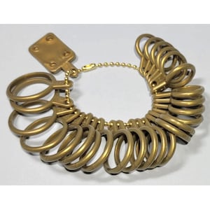 May include: A gold-colored plastic ring sizer with a chain and a tag. The sizer has 20 rings of different sizes.