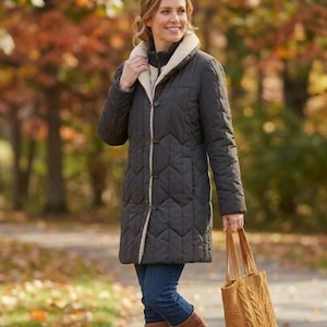 May include: A charcoal grey quilted coat featuring a chevron pattern, a cream-coloured faux fur collar, and a front button closure. The coat is paired with dark blue denim jeans, brown leather knee-high boots, and a mustard yellow cable-knit tote bag.