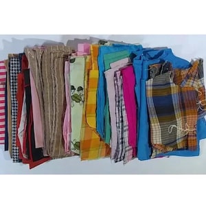 May include: A collection of fabric scraps in various colors and patterns, including stripes, plaid, and floral prints. The scraps are arranged in a stack, with the top of the stack being the most recent addition.