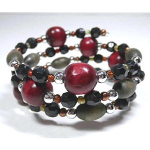 May include: A triple-strand bracelet featuring red wooden beads, black faceted beads, and green oval beads.