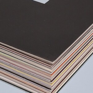 May include: A stack of black and white photo mats with various colored edges. The mats are stacked on top of each other, with the top mat being black and the bottom mats showing a variety of colors.