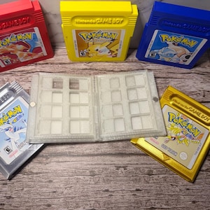 May include: A collection of Pokemon Game Boy cartridges in red, yellow, blue, silver, and gold. The cartridges are labeled with the Pokemon logo and character illustrations. A clear plastic game cartridge holder is also present.