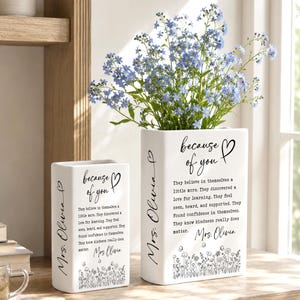May include: Two white rectangular ceramic vases featuring black printed text that reads because of you, Mrs. Olivia, and a paragraph about kindness and learning. The vases are decorated with a black line art illustration of wildflowers at the base.